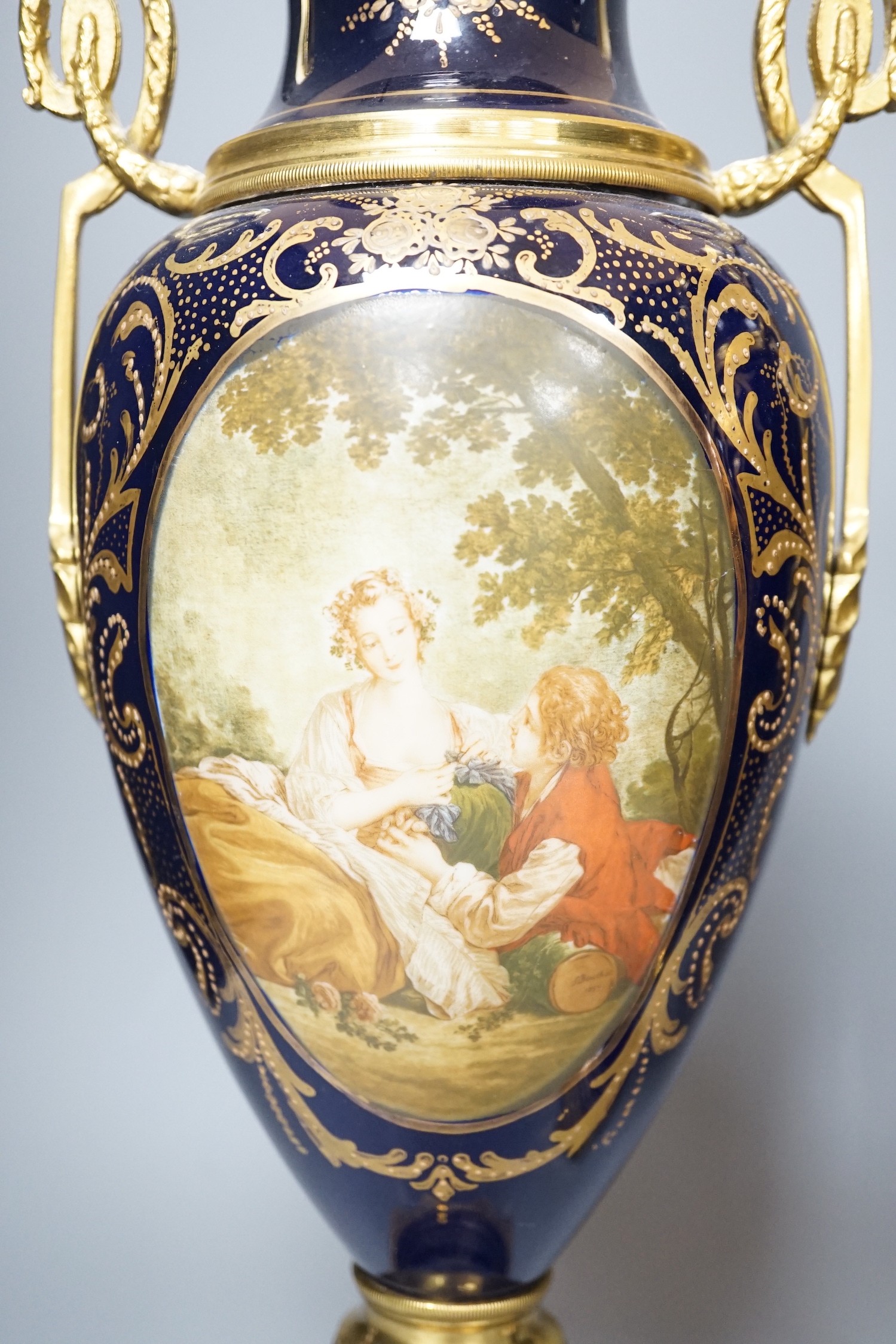 A pair of Sevres style urns and covers, with gilt metal mounts, 50 cms high